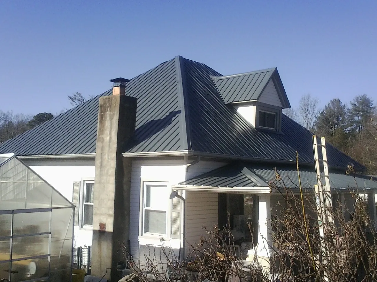 Dark blue standing seam metal roof on a white farmhouse with dormer — Slate & Tile Roof Repair by Roofing Brothers in Stephens City