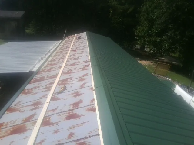 Old rusted panels beside newly installed green metal roofing — Wind Damage Roof Repair by Roofing Brothers in Stephens City