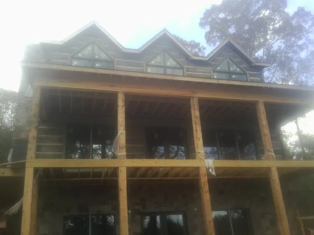 Dormers and porch framing on a large log home under construction — Roof Coating work by our crew in Stephens City