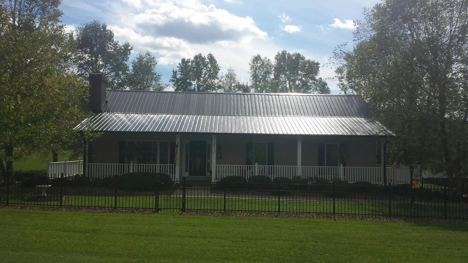 Gray metal roof on a brick ranch with a full width front porch — Gutter Guard Installation work by our crew in Stephens City