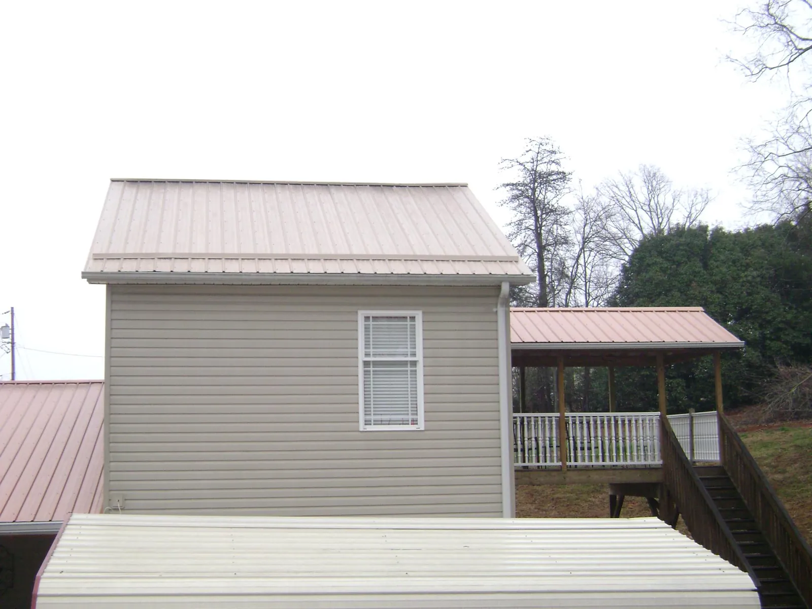 Tan metal roofs on a two story addition and attached porch, from a Roof Replacement job in Stephens City