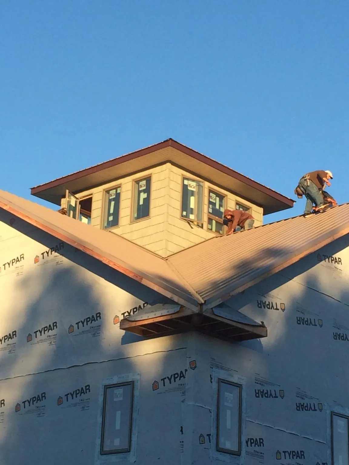 Roofers working around a rooftop cupola on a new metal roof at sunset — Roof Waterproofing in Stephens City by Roofing Brothers